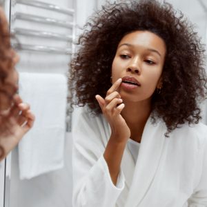 young woman looking at lips in the bathroom mirror