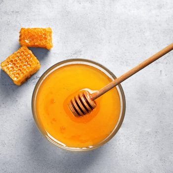 Glass bowl with delicious honey and dipper on table