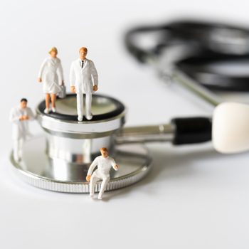 Miniature people, Doctor and Nurse emergency medical team on stethoscope on white background. Health care, life insurance travel hospitality concept.