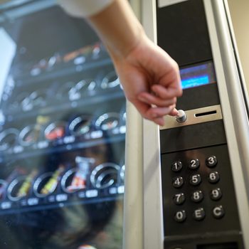 sell, technology and consumption concept - hand pushing button on vending machine operation panel