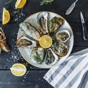 Open wet oysters on a plate with lemon