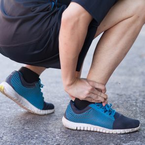 Runner touching painful twisted or broken ankle. Athlete runner training accident. Sport running ankle sprain. 