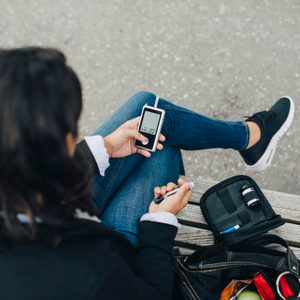 Woman checking blood sugar level while sitting on bench