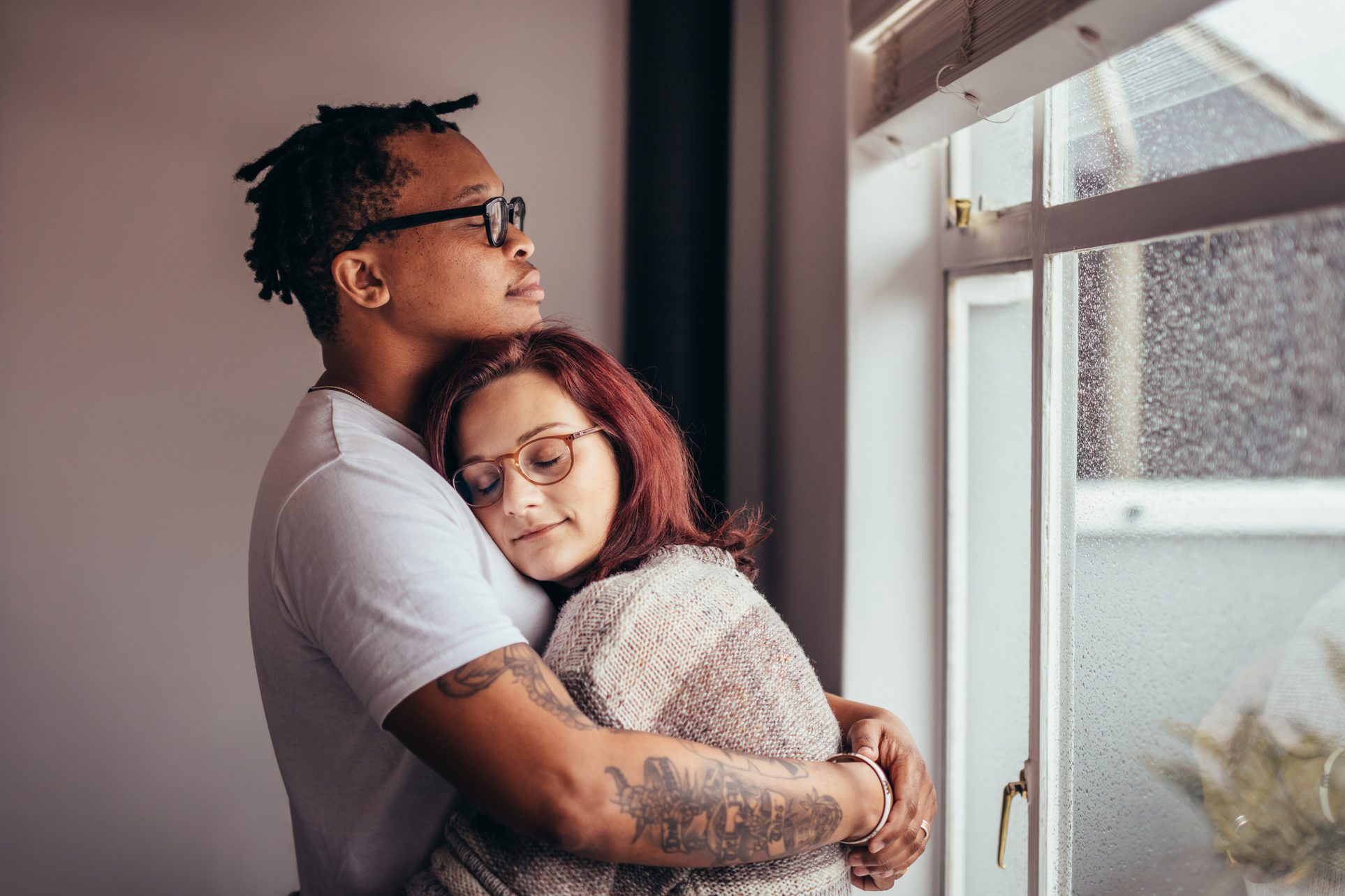 young couple hugging near window