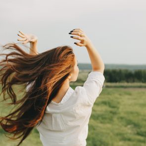 Close up portrait of beautiful carefree long hair girl in white clothes in field, view from back. Sensitivity to nature concept