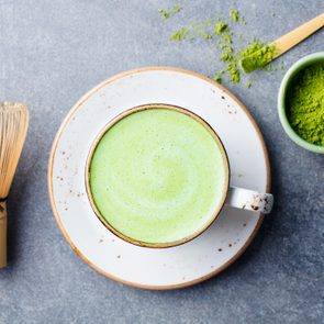 Matcha green tea latte in a cup with bamboo whisk. Top view.