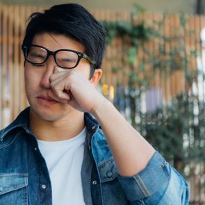 Young Man Rubbing Eye With Hand