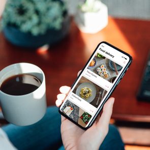 Close up shot of woman ordering food delivery via food delivery app on her mobile phone