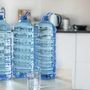 Big plastic bottle with water on the table over bright kitchen backgroung.