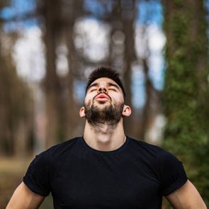 Relaxed man breaths fresh air in a beautiful colorful forest