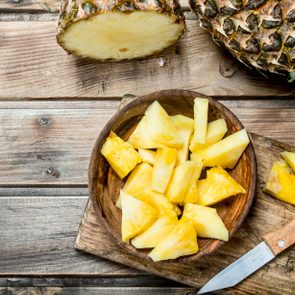 Pieces of fragrant pineapple in a bowl on a cutting Board with a knife.