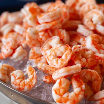 Large tray of cooked shrimp on ice