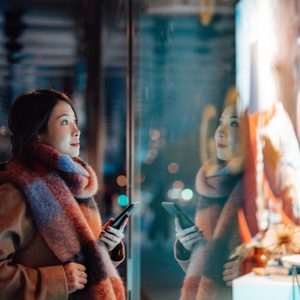 Young woman window shopping in the city at night