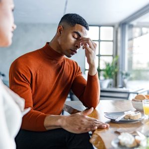 Frustrated couple arguing during meal in dining room.