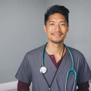 Portrait of nurse with stethoscope standing against wall in hospital