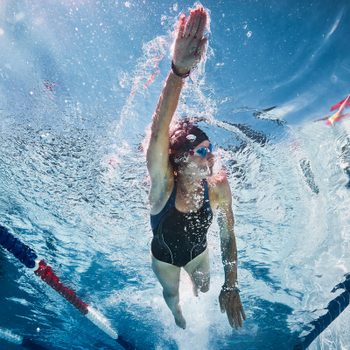 woman swimming in a pool, view from below under water