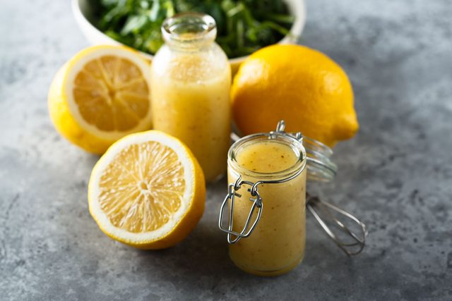 citrus Salad Dressing with lemons and salad in the background on gray surface